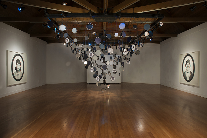 Lava Thomas, Looking Back and Seeing Now, 2015. Site-specific installation including: Tambourine installation, altered tambourines, lambskin, leather, ribbon, acrylic mirrors, digital prints, glue, monofilament wire, s-hooks, wood, and steel, 15 x 12 x 20 ft.; Looking Back 1. Graphite, conté pencil, charcoal, and watercolor on paper. 72 x 72 in.; Looking Back 2. Graphite, conté pencil, charcoal, and watercolor on paper. 72 x 72 in.